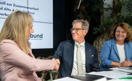 Die Präsidentin von Coopbund, Monica Devilli, freut sich mit Herbert Von Leon, Obmann des Raiffeisenverbandes, über die vertiefte Zusammenarbeit. Im Bild rechts die Landesrätin für das Genossenschaftswesen Rosmarie Pamer.